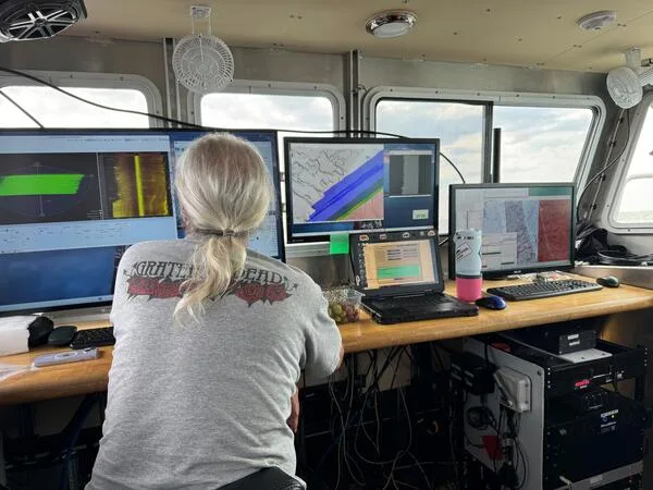 Scientists reviewing seafloor mapping data onboard a research vessel
