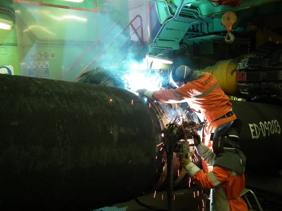Two pipe sections being welded together aboard a pipelaying vessel