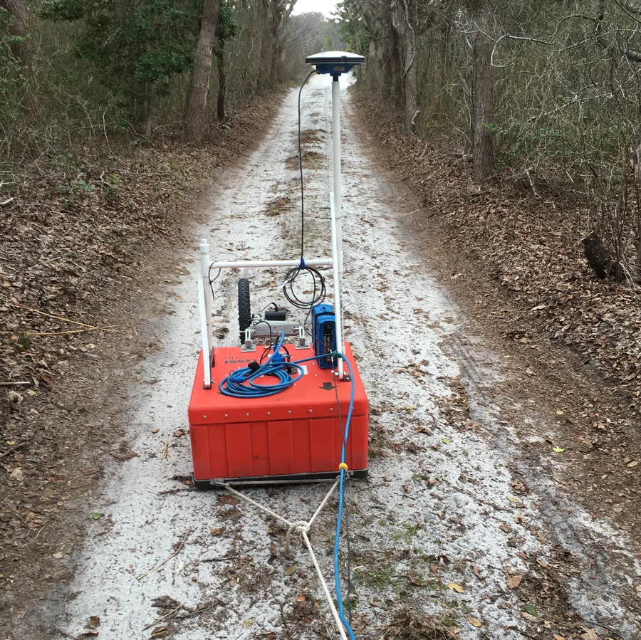 Ground-penetrating radar equipment being towed along the ground behind dunes at Fire Island, New York