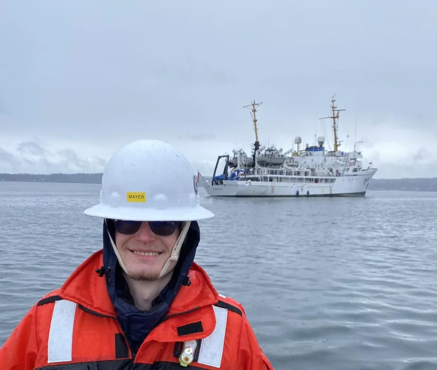 A NOAA hydrographic senior survey technician standing in front of a survey vessel