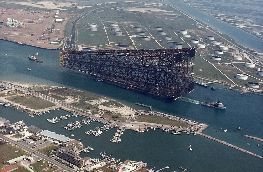 The jacket of the Bullwinkle offshore oil platform being towed out to sea through a Texas channel