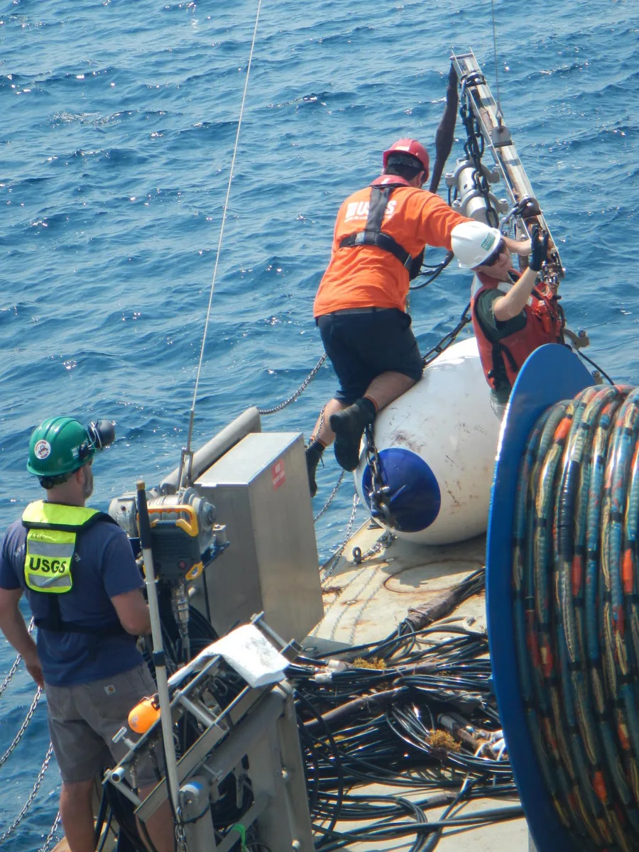 USGS personnel aboard a research vessel retrieving a seismic streamer and airgun equipment onto a winch