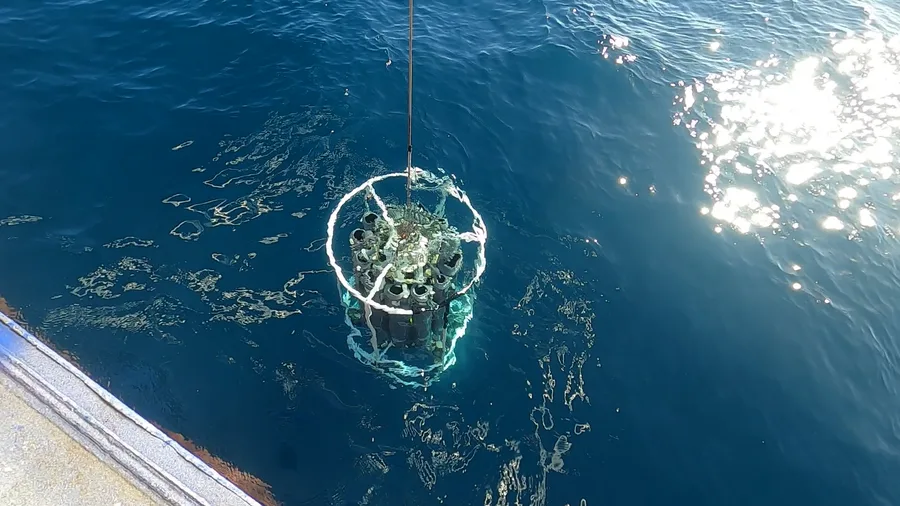 A CTD rosette instrument being lowered into the ocean from a survey vessel